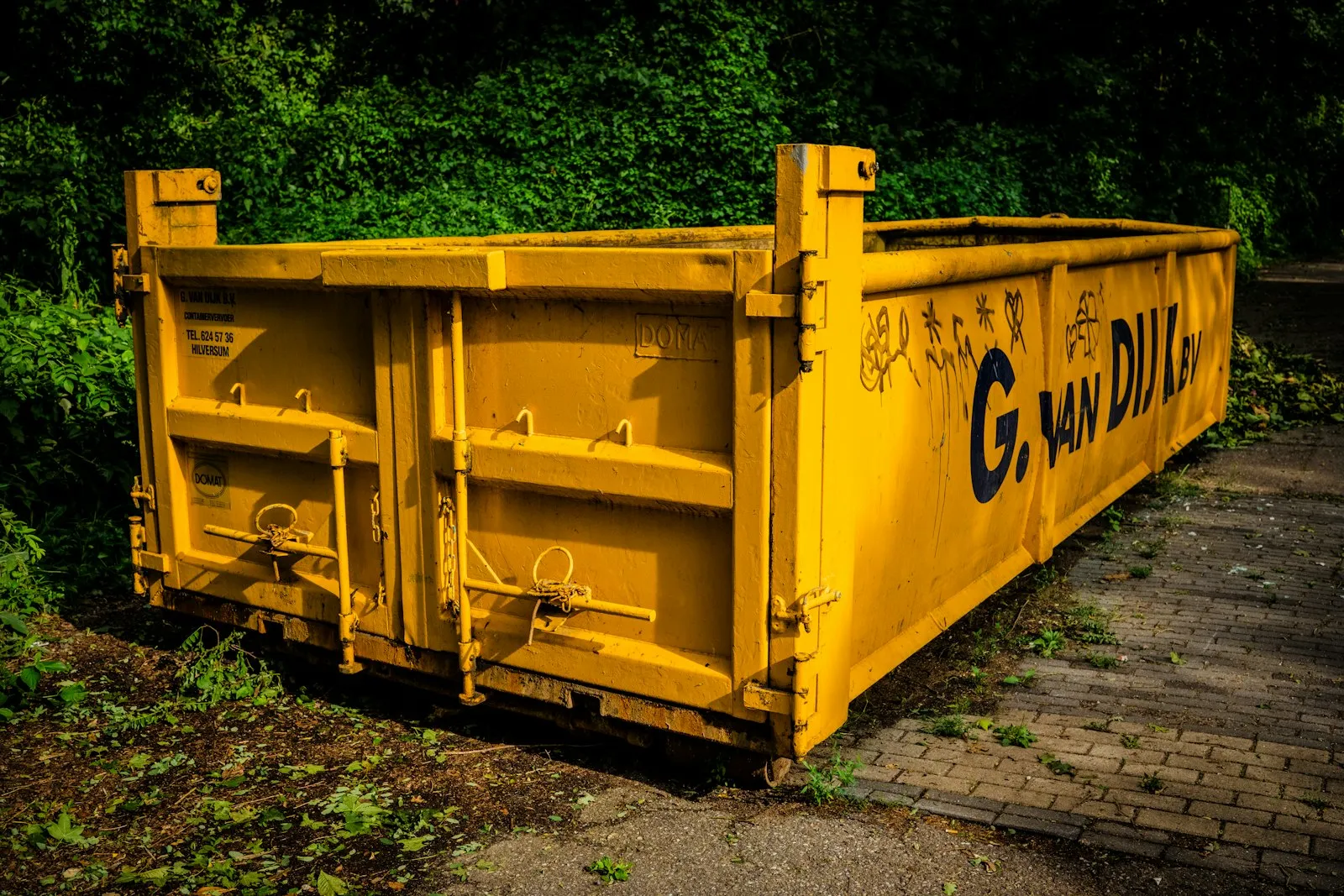 A roll-off dumpster parked on the side of a road